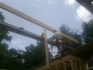 Carpenter setting a ridge beam over a new addition frame — Ice Dam Removal by Roofing Brothers in Hall