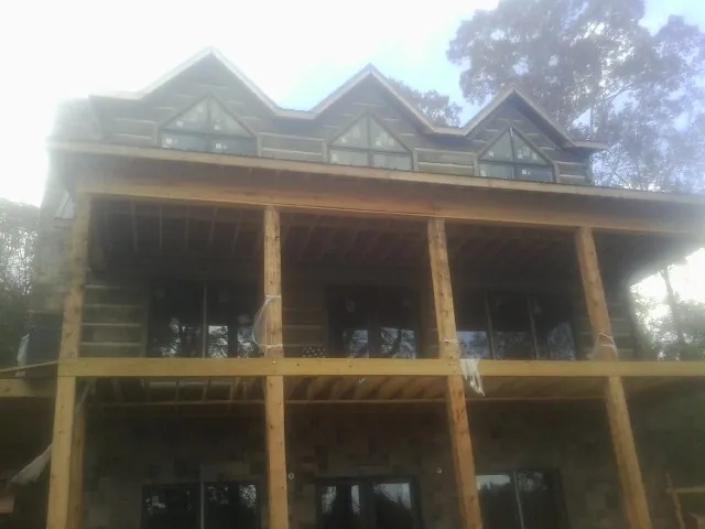 Dormers and porch framing on a large log home under construction — Roof Coating work by our crew in Hall
